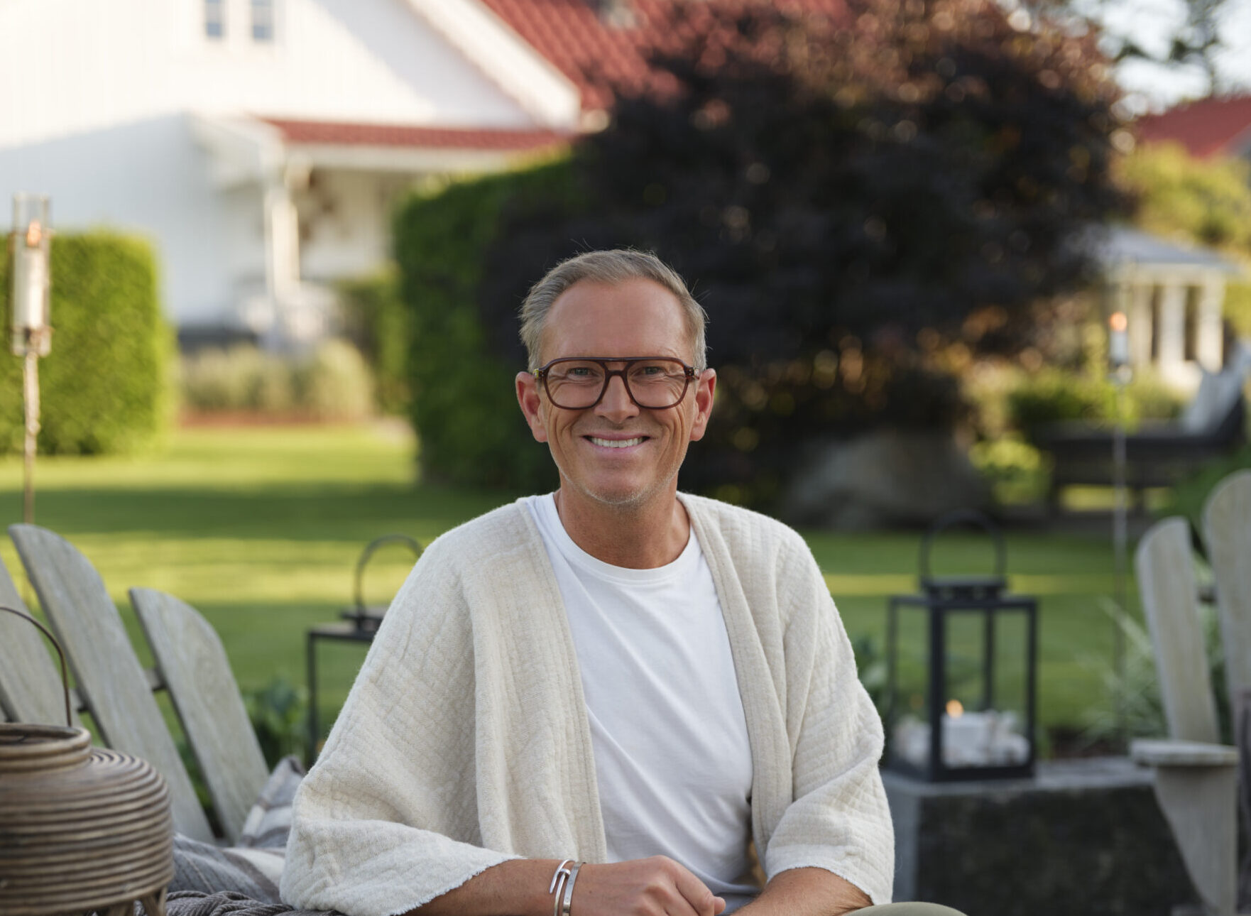 Halvor sitter i en trädgårdsstol ute i en sommarträdgård.