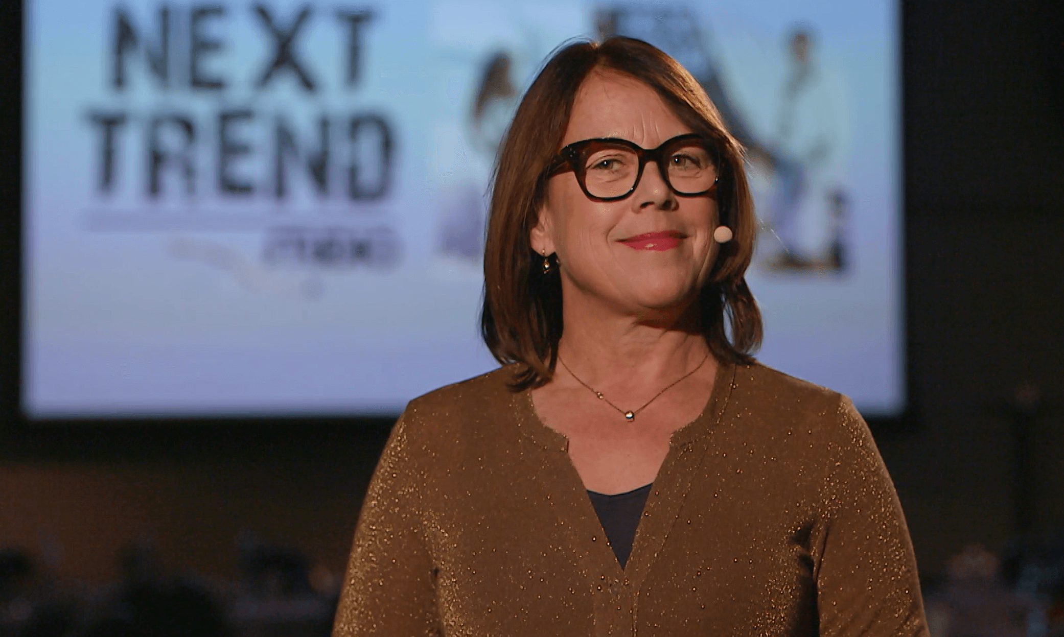 Louise står på scenen och ler in i kameran.