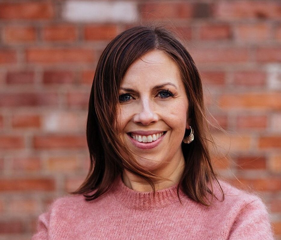 Maria_Soxbo Maria står i en stickad tröja och ler in i kameran.